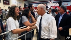 In this Sept. 29, 2014 photo, U.S. Representatives Mike Coffman (C) and Cory Gardner, R-Colo., greet students attending a political rally at Heritage High School, in the Denver suburb of Littleton, Colo. (AP Photo/Brennan Linsley)