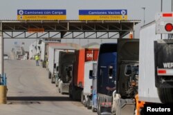 FILE - Trucks wait in a long queue for border customs control to cross into the U.S. at the Otay border crossing in Tijuana, Mexico, Feb. 2, 2017.