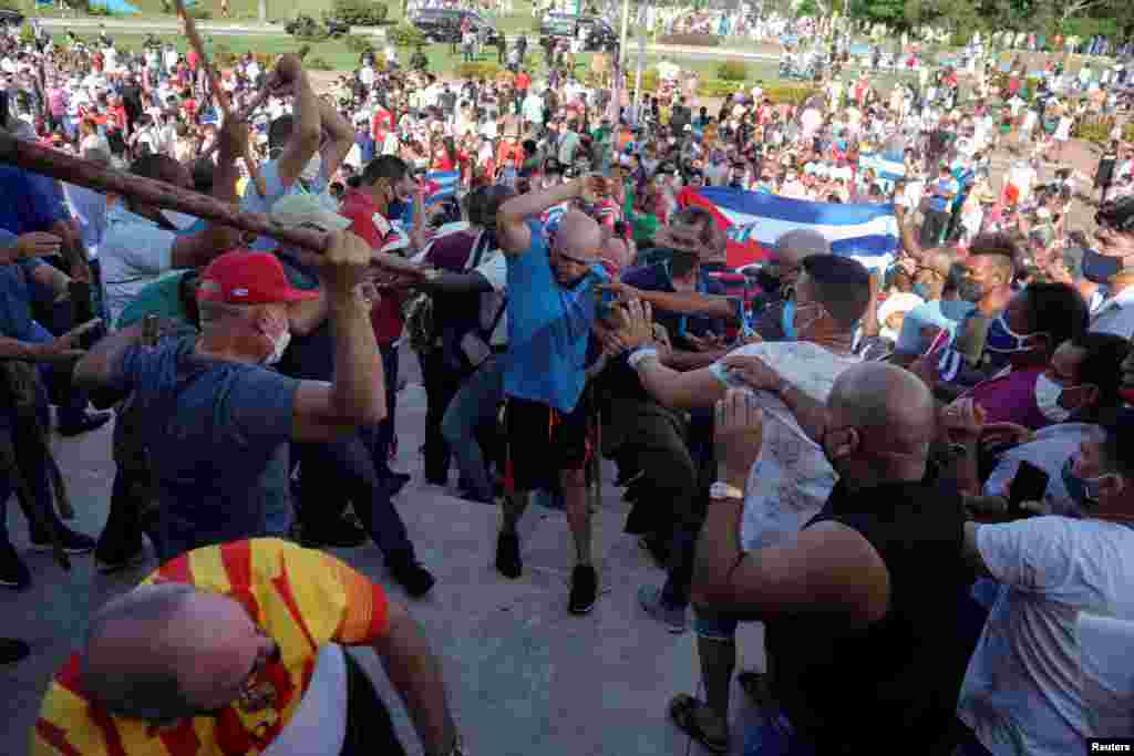 People clash with plain clothes police during protests against and in support of the government, during the continued COVID-19 crisis, in Havana, Cuba, July 11, 2021.