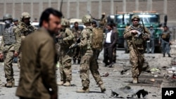 FILE - US forces and Afghan security inspect the site after a suicide bombing attack near Kabul's international airport in Kabul, Afghanistan, May 17, 2015. 