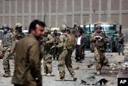 FILE - US forces and Afghan security inspect the site after a suicide bombing attack near Kabul's international airport in Kabul, Afghanistan, May 17, 2015.