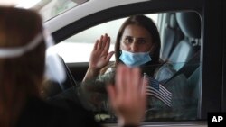 In this Friday, June 26, 2020 photo, U.S. District Judge Laurie Michelson, left, the Aath of Citizenship to Hala Baqtar during a drive-thru naturalization service in a parking structure at the U.S. Citizenship and Immigration Services headquar