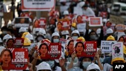 Para pengunjuk rasa mengangkat spanduk yang menuntut pembebasan pemimpin Myanmar yang ditahan Aung San Suu Kyi selama demonstrasi menentang kudeta militer 1 Februari di Yangon pada 10 Februari 2021. (Foto: AFP/Ye Aung Thu)