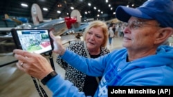 In this Friday, April 26, 2019 photo, Deane Sager, of Louisville, right, and his wife Cathy use a Histopad tablet to view scenes from operations on the western front of World War II at the The National Museum of the U.S. Air Force, in Dayton, Ohio. (AP Photo/John Minchillo)