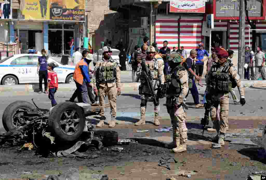 People and security forces inspect the site of a car bomb attack in Sadr City, Baghdad, August 28, 2013.