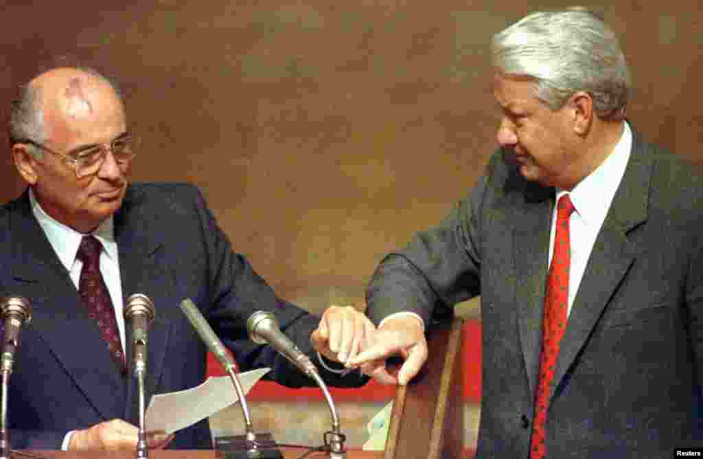 Then Russian President Boris Yeltsin and then Soviet President Mikhail Gorbachev touch hands during Gorbachev's address to the Extraordinary meeting of the Supreme Soviet of Russian Federation in Moscow, August 23, 1991.