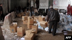 FILE - Aid parcels and boxes are offloaded from vehicles in a warehouse in Idlib, in northwestern Syria.