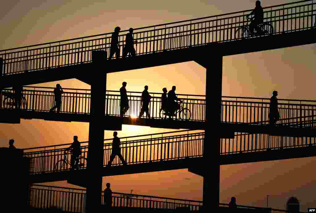 Laborers cross a pedestrian bridge in Dubai, United Arab Emirates.