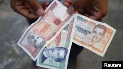 FILE - A man shows a new Cuban pesos outside a bank in Havana, Feb. 2, 2015. 