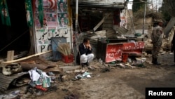 A shopkeeper sits outside his shop, after it was damaged by a bomb attack in Quetta, Pakistan, April 24, 2013.