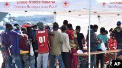 Les migrants s’alignent devant une tente de la Croix-Rouge après avoir débarqué du navire irlandais Marine LE Niamh au port de Messine, en Sicile, Italie, 24 août 2015. (AP Photo / Carmelo Imbesi)