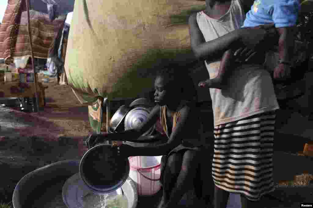 Uma menina sul-sudanesa lava pratos no campo de refugiados da UNMISS em Tongping, Juba, Sudão do Sul, Fev. 19, 2014.&nbsp;