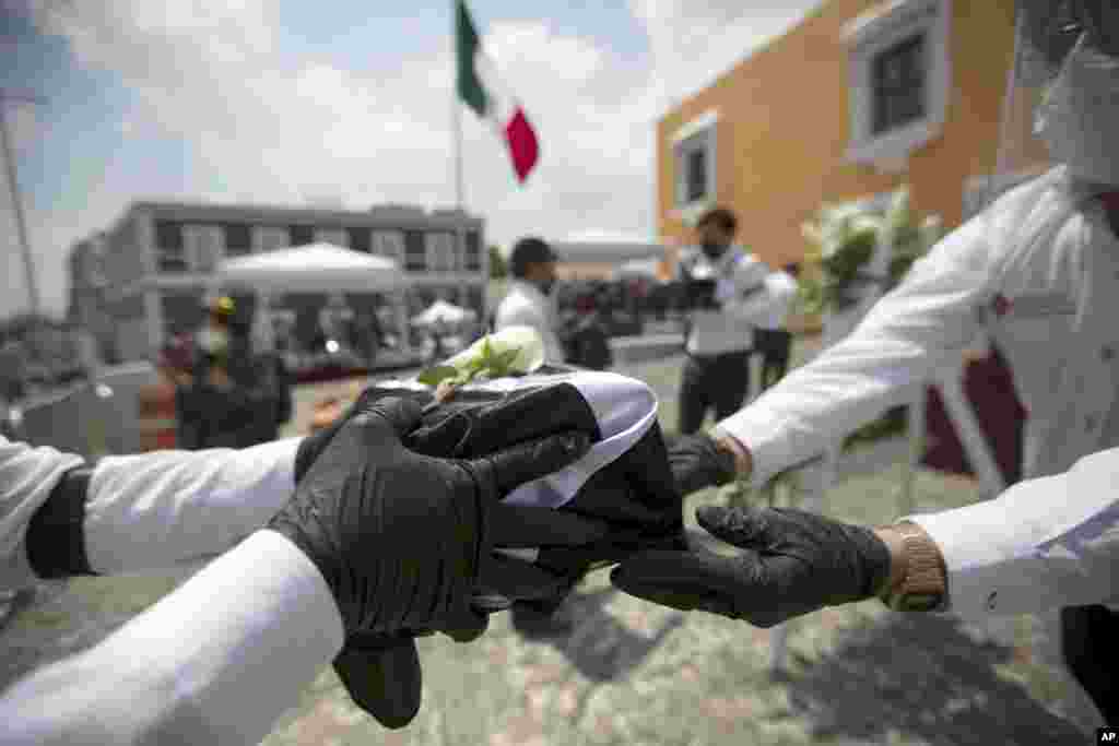 Puebla state workers handle an urn holding ashes of a Mexican who died in the U.S. from COVID-19, during a ceremony in Puebla, Mexico, July 13, 2020. The remains of 105 Mexicans who died in the U.S. of the new coronavirus were returned to their families.
