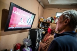 Warga menyaksikan siaran langsung Presiden Joko Widodo disuntik perdana vaksin Covid-19 di Jakarta, Rabu, 13 Januari 2021. (Foto: Aprilio Akbar/Antara Foto via Reuters)
