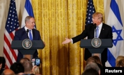 U.S. President Donald Trump, right, reaches out to Israeli Prime Minister Benjamin Netanyahu during a joint news conference at the White House in Washington, Feb. 15, 2017.