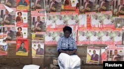 FILE - A woman sits in front of campaign posters in Nairobi, Kenya, April 26, 2017.