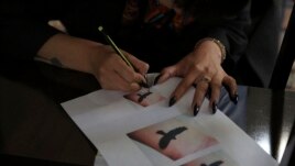 In this Saturday, November 9, 2019, photo, Suraya Shaheedi, 26, Tattoo artist, takes a copy of tattoo before a pierced tattoo to her male customer in Kabul, Afghanistan.