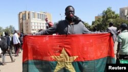 Homem ergue bandeira do Burkina Faso durante uma manifestação de apoio aos militares após a detenção do Presidente Roch Kabore. 24 Janeiro 2022