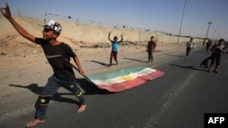 An Iraqi boy drags a Kurdish flag as Iraqi forces advance towards the center of Kirkuk during an operation against Kurdish fighters on Oct. 16, 2017. 