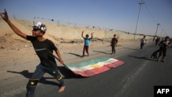 Un niño iraquí arrastra la bandera kurda mientras las fuerzas iraquíes avanzan hacia el centro de Kirkuk durante una operación contra combatientes kurdos el 16 de octubre de 2017.