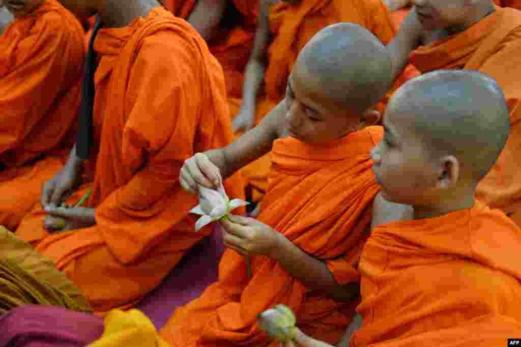 A young Indian Buddhist monk opens the petals of a lotus flower as he sits with others while offering prayers on the occasion of Buddha Purnima in Bangalore, during the 2559th Buddha Jayanthi or birth celebrations of Buddha.