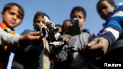 FILE - Boys hold missile shrapnel they collected from the site of a Saudi-led airstrike in the Houthi-held capital of Sanaa, Yemen, Jan. 20, 2019.