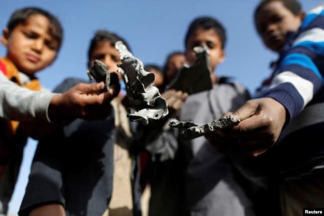FILE - Boys hold missile shrapnel they collected from the site of a Saudi-led airstrike in the Houthi-held capital Sana'a, Yemen, Jan. 20, 2019.