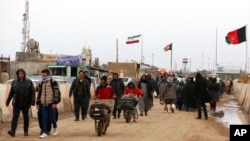FILE- Afghans return to Afghanistan at the Islam Qala border with Iran, in the western Herat province, Feb. 20, 2019. "A misunderstanding" over the border demarcation sparked a conflict near the Afghan province of Nimruz on Dec. 1, 2021, the two countries confirmed.