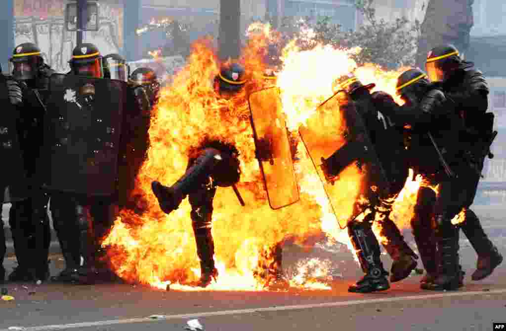 French CRS anti-riot police officers are engulfed in flames as they face protesters during a march for the annual May Day workers&#39; rally in Paris.