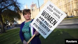 FILE - Labour Party member of Parliament Emily Thornberry holds a placard at an event to mark the 100th anniversary of the enfranchisment of some, but not all women, outside the Houses of Parliament in London, Britain, Feb. 6, 2018.