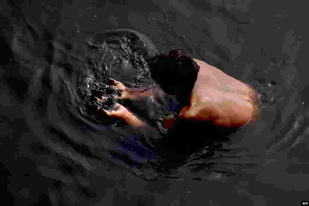 A man looks for valuables in the polluted Yamuna River in New Delhi, India.