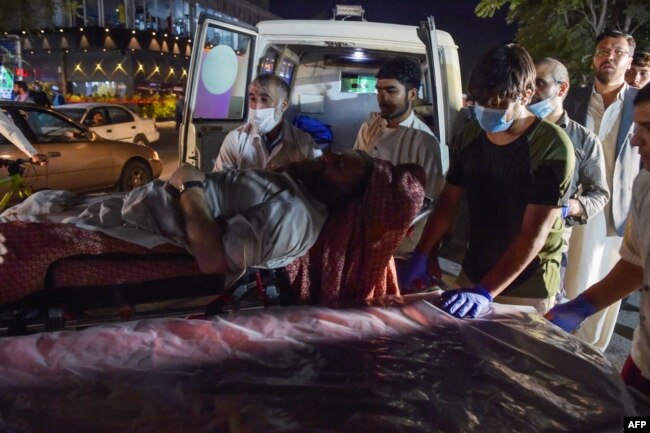 Volunteers and medical staff bring an injured man for treatment after two powerful explosions outside the airport in Kabul on Aug. 26, 2021.
