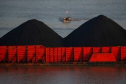 Seorang pria berdiri di atas kapal saat tongkang batu bara antri untuk ditarik di sepanjang sungai Mahakam, Samarinda, provinsi Kalimantan Timur, 31 Agustus 2019. (REUTERS/Willy Kurniawan)