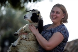 Shepherdess Jenna Lewinsky holds a lamb in Ramot Naftali, Israel, Feb. 21, 2018. (REUTERS Photo/Amir Cohen)