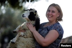 Shepherdess Jenna Lewinsky holds a lamb in Ramot Naftali, Israel, Feb. 21, 2018. (REUTERS Photo/Amir Cohen)