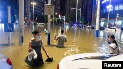Des personnes pataugent dans l'eau de crue à une intersection après que de fortes pluies ont entraîné des inondations à Hefei, dans la province d'Anhui, en Chine, le 27 juin 2020. Photo prise le 27 juin 2020.