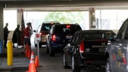 In this June 26, 2020 photo, cars line up during a drive-thru naturalization service in a parking structure at the U.S. Citizenship and Immigration Services headquarters on Detroit's east side. (AP Photo/Carlos Osorio)