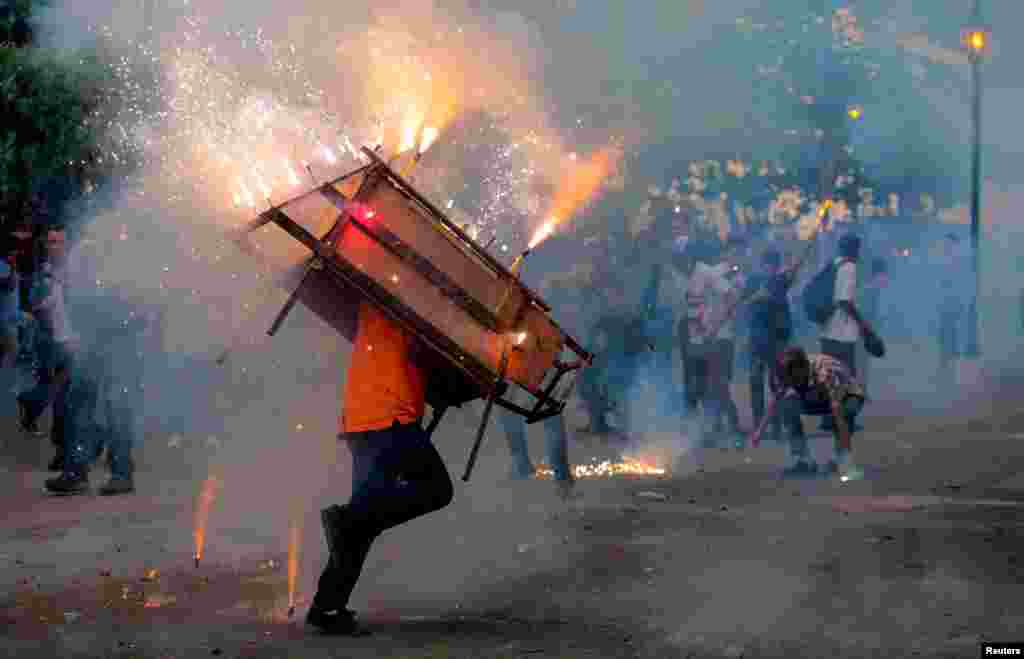 A man runs with a &quot;toro encuetado&quot; &mdash; a structure resembling a bull and emitting exploding firecrackers &mdash; during celebration in honor of the Virgin Mary in Leon, Nicaragua, Aug.14, 2018.
