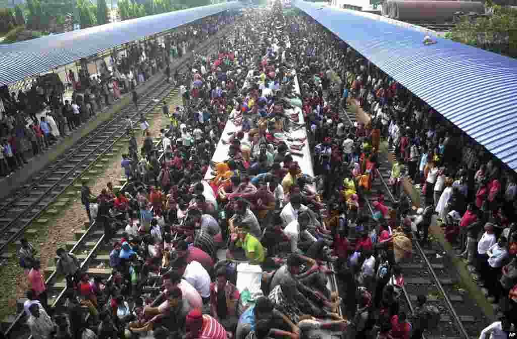 Muslims travel on the roof of a train as they head to their homes ahead of Eid al-Adha as others wait at a railway station in Dhaka, Bangladesh, Oct. 15, 2013. 