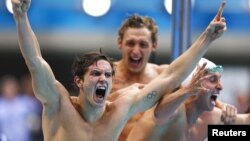 法国游泳选手在他们的队友阿涅尔在男子4x100米自由泳接力中游最后一个来回时振臂为他加油