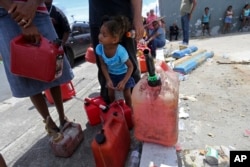 Abi de la Paz de la Cruz, 3, holds a gas can as she waits in line with her family, to get fuel from a gas station, in the aftermath of Hurricane Maria, in San Juan, Puerto Rico, Sept. 25, 2017.