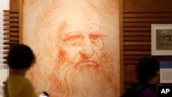 FILE - Visitors look at a portrait of Italian Renaissance painter, scientist and inventor Leonardo da Vinci during an exhibition in Rome, May 2, 2019. 