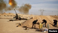 FILE - Libya Dawn fighters fire an artillery cannon at Islamic State militants near Sirte.