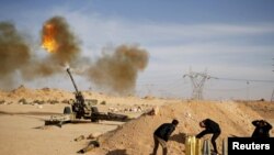 FILE - Libya Dawn fighters fire an artillery cannon at Islamic State militants near Sirte, March 19, 2015.