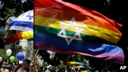 FILE - Israelis and tourists wave flags as they participate in the Gay Pride parade in Tel Aviv, Israel, June 8, 2018.