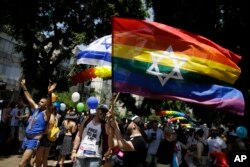 Israelis and tourists wave flags as they participate in the Gay Pride parade in Tel Aviv, Israel, June 8, 2018.