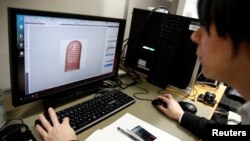 Tateo Ogane, a researcher of at Japan's National Institute of Informatics, works to analyse Isao Echizen's fingerprint covered with a home-made biometric jammer during a demonstration of their experiment for Reuters in Tokyo, Jan. 13, 2017. 