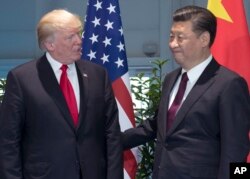 FILE - , U.S. President Donald Trump, left, and Chinese President Xi Jinping arrive for a meeting on the sidelines of the G-20 Summit in Hamburg, Germany.