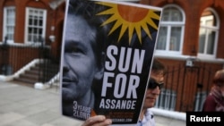 A supporter of WikiLeaks founder Julian Assange holds a placard during a gathering outside the Ecuadorian Embassy in London, June 19, 2015. 