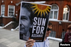 Seorang pendukung pendiri WikiLeaks Julian Assange memegang sebuah placard dalam sebuah pertemuan di luar kedutaan Ekuador di London, 19 Juni 2015.